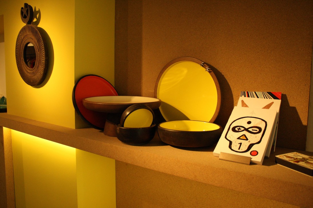 Colorful ceramics and decorative items displayed on a shelf with yellow and warm lighting.