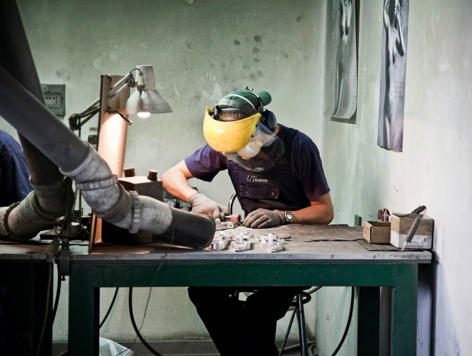 Worker in yellow safety mask and helmet operating machinery at metal-cutting workshop at Ultratech Rzeszów.