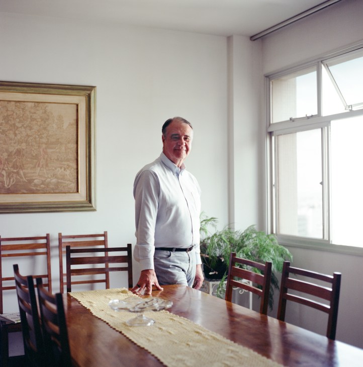 Aguinaldo Diniz, director of Cedro Cachoeira textile company, stands at a table in a bright office with wooden chairs.