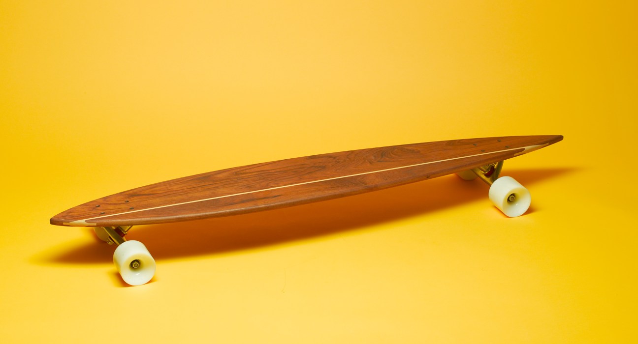 Loki longboard skateboard made from antique wood with white wheels on yellow background.