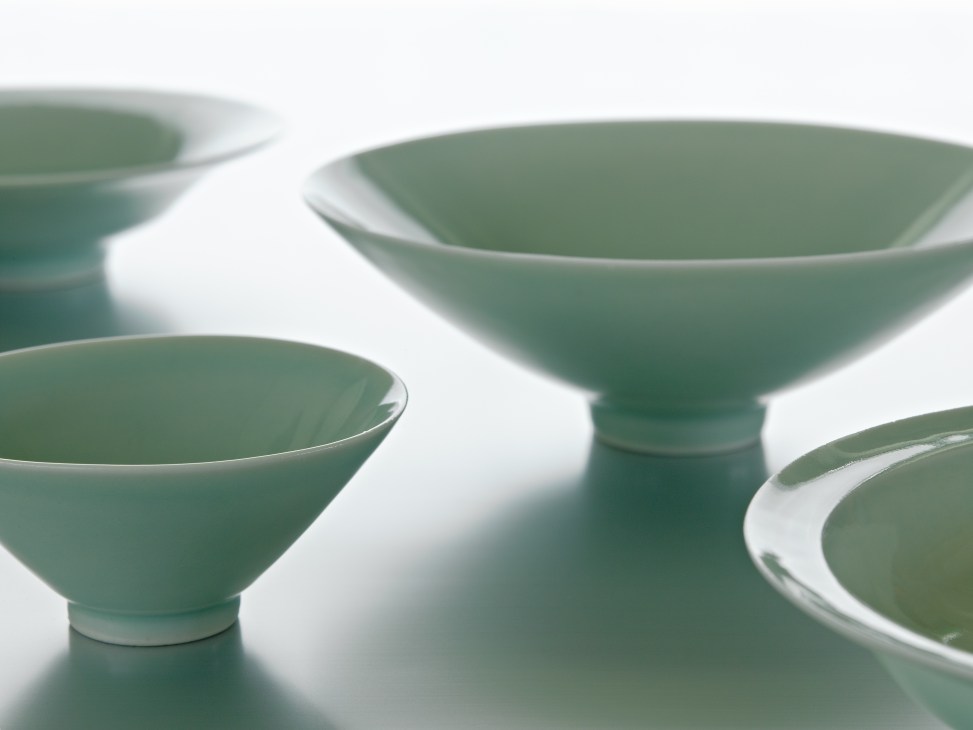Green porcelain bowls with white rims from Jingdezhen displayed against a white background.