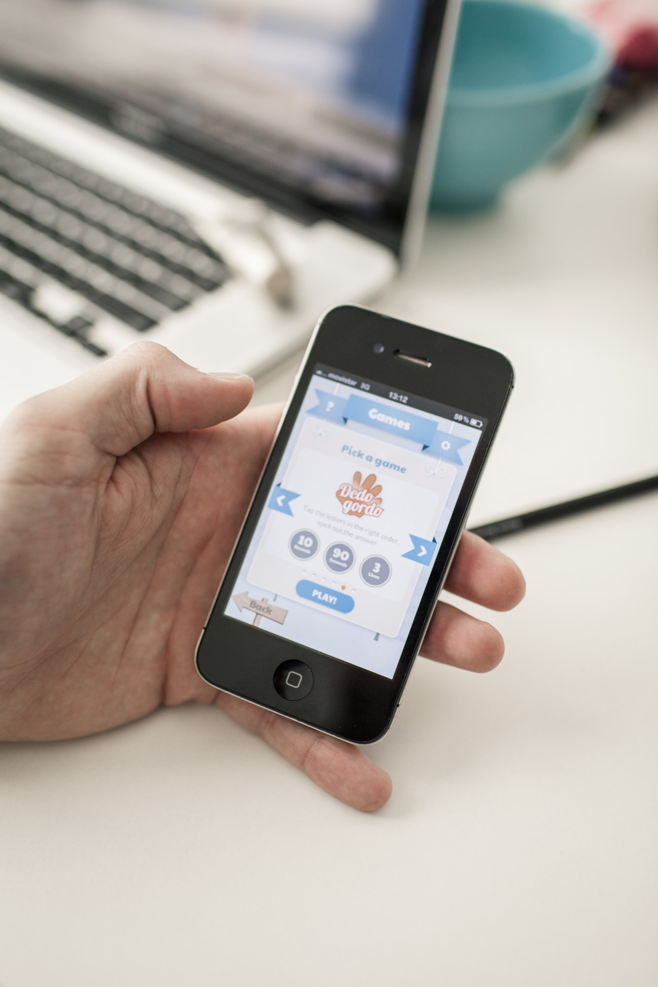 Hand holding smartphone displaying uSpeak language learning app with game selection screen.