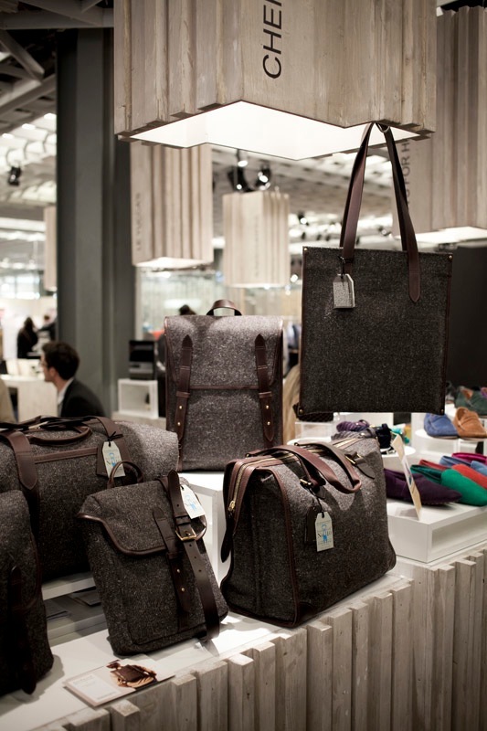 Herdwyck by Cherchbi wool bags displayed at a trade show booth with leather handles.