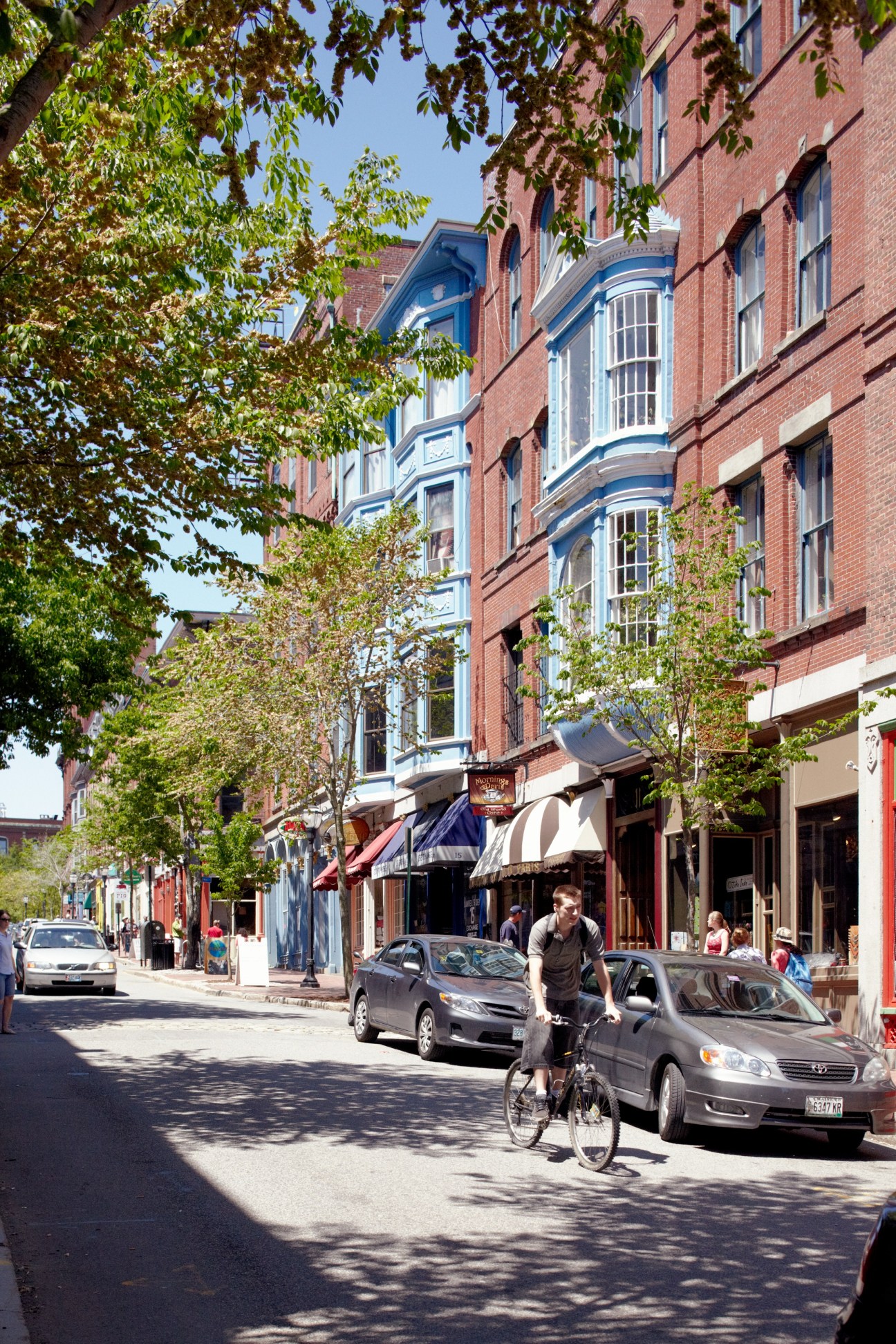 Cyclist riding on Exchange Street in Portland with historic red-brick buildings and storefronts.