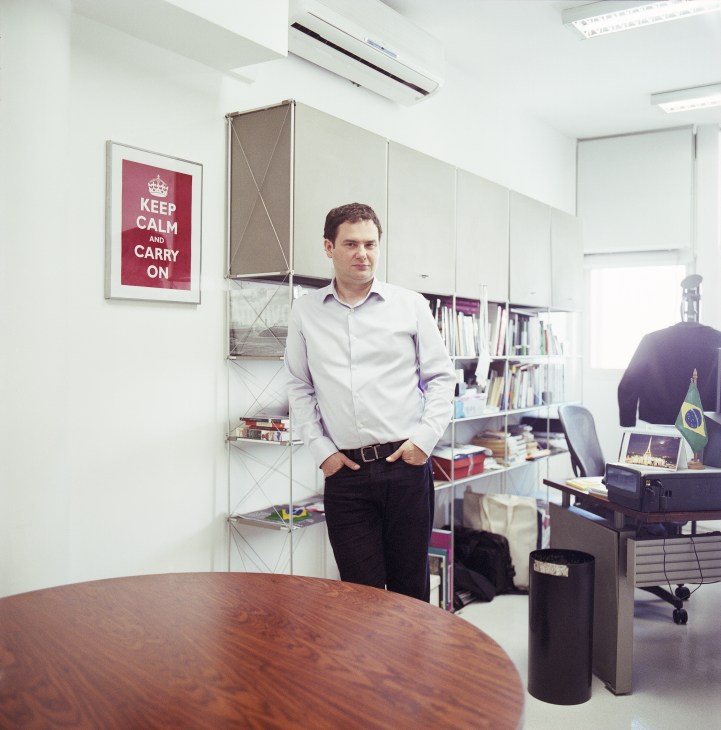 Sérgio Dávila, editor-in-chief of Folha de S.Paulo, stands in his office with bookshelves and Brazilian flag visible.