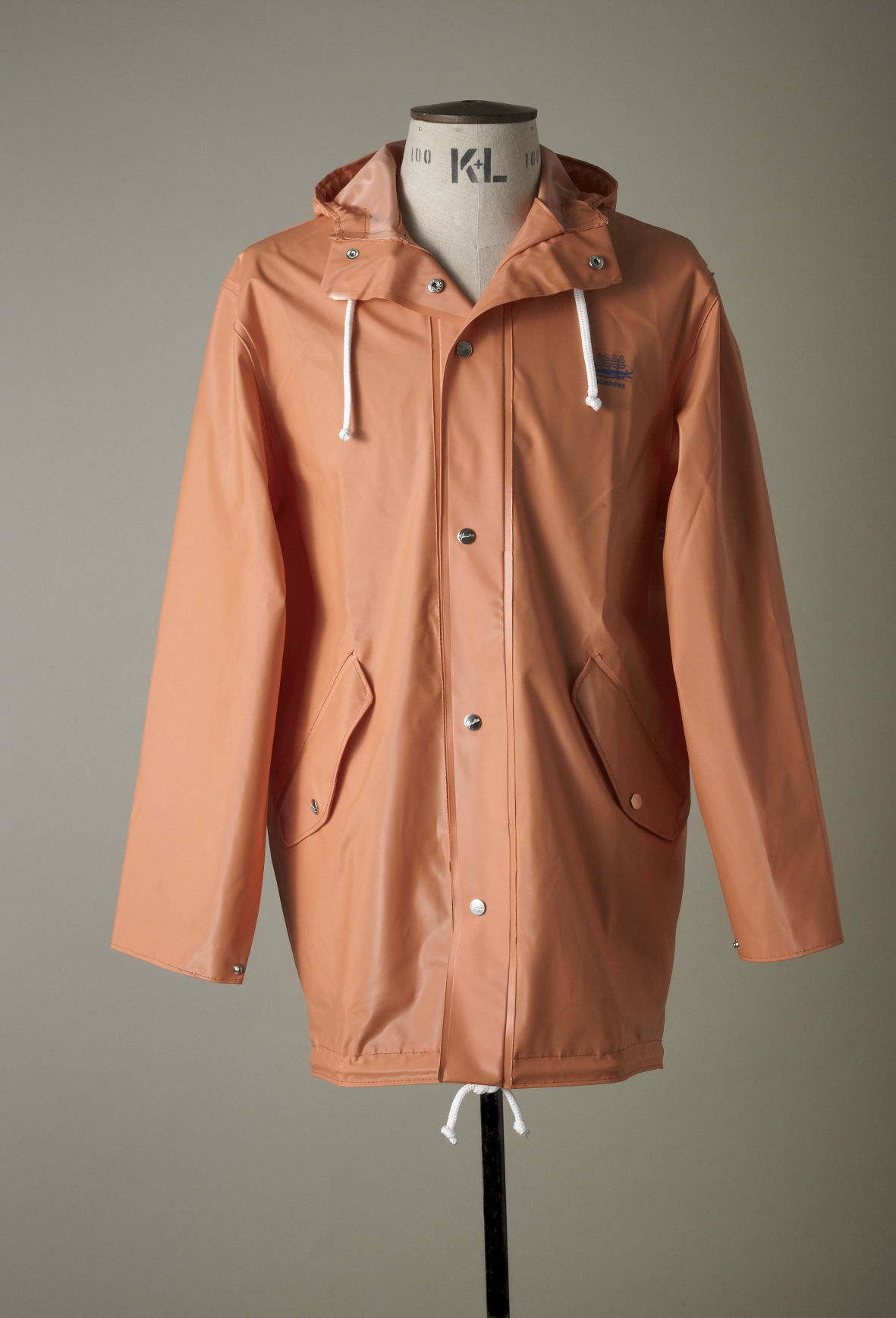 Coral-pink Grundéns waterproof parka with hood and white drawstrings displayed on a dress form.