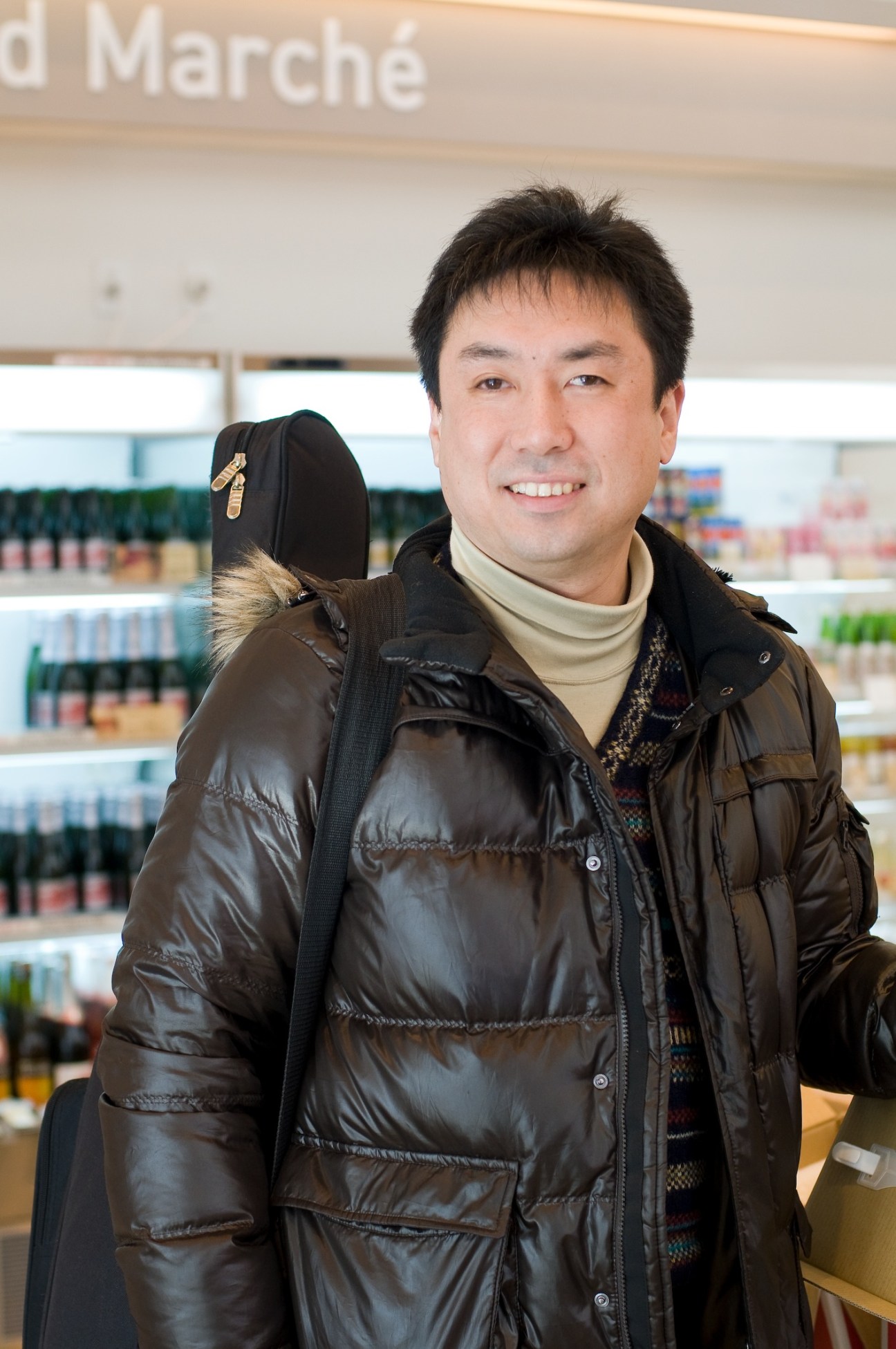 Man in black puffer jacket smiling at camera inside Food Marché at A-Factory.
