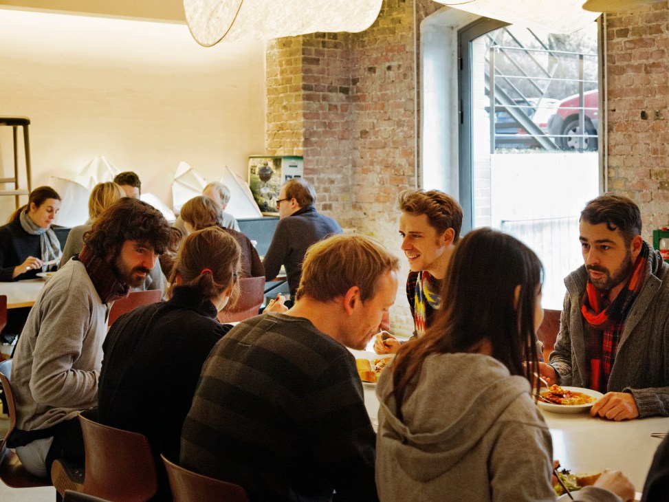 Sauerbruch Hutton office staff gather around a table eating lunch provided by a local chef.