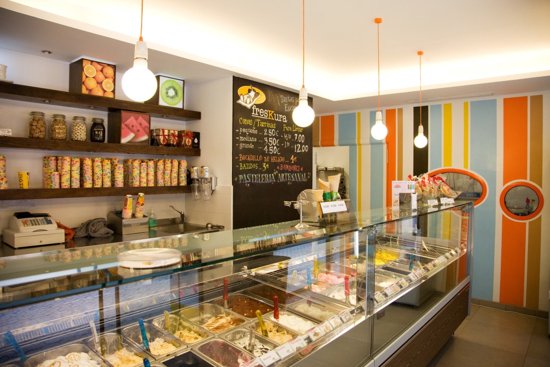 Interior of Freskura ice cream shop with display counter and colorful striped wall.