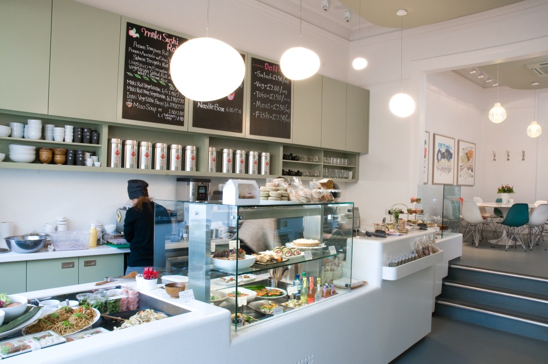 Interior of Tombo Japanese restaurant and deli in London showing counter with display cases, menu boards and pendant lighting.