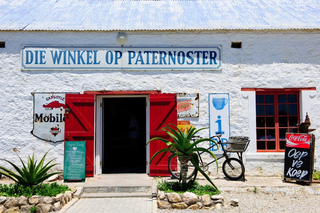 Oep Ve Koep Bistro storefront in Paternoster with white walls, red doors and vintage signage.