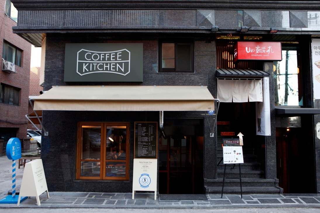 Coffee Kitchen storefront in Seoul with signage and wooden entrance doors on dark facade.