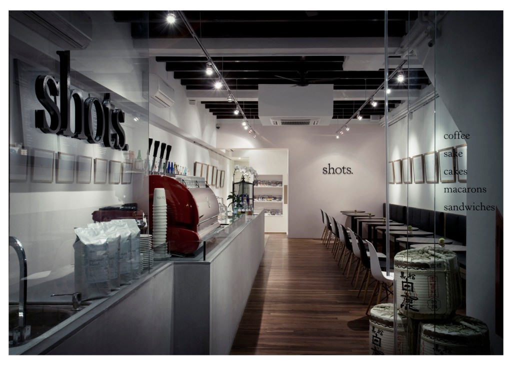 Interior of Shots Café in Singapore showing counter with red espresso machine and menu items listed on wall.