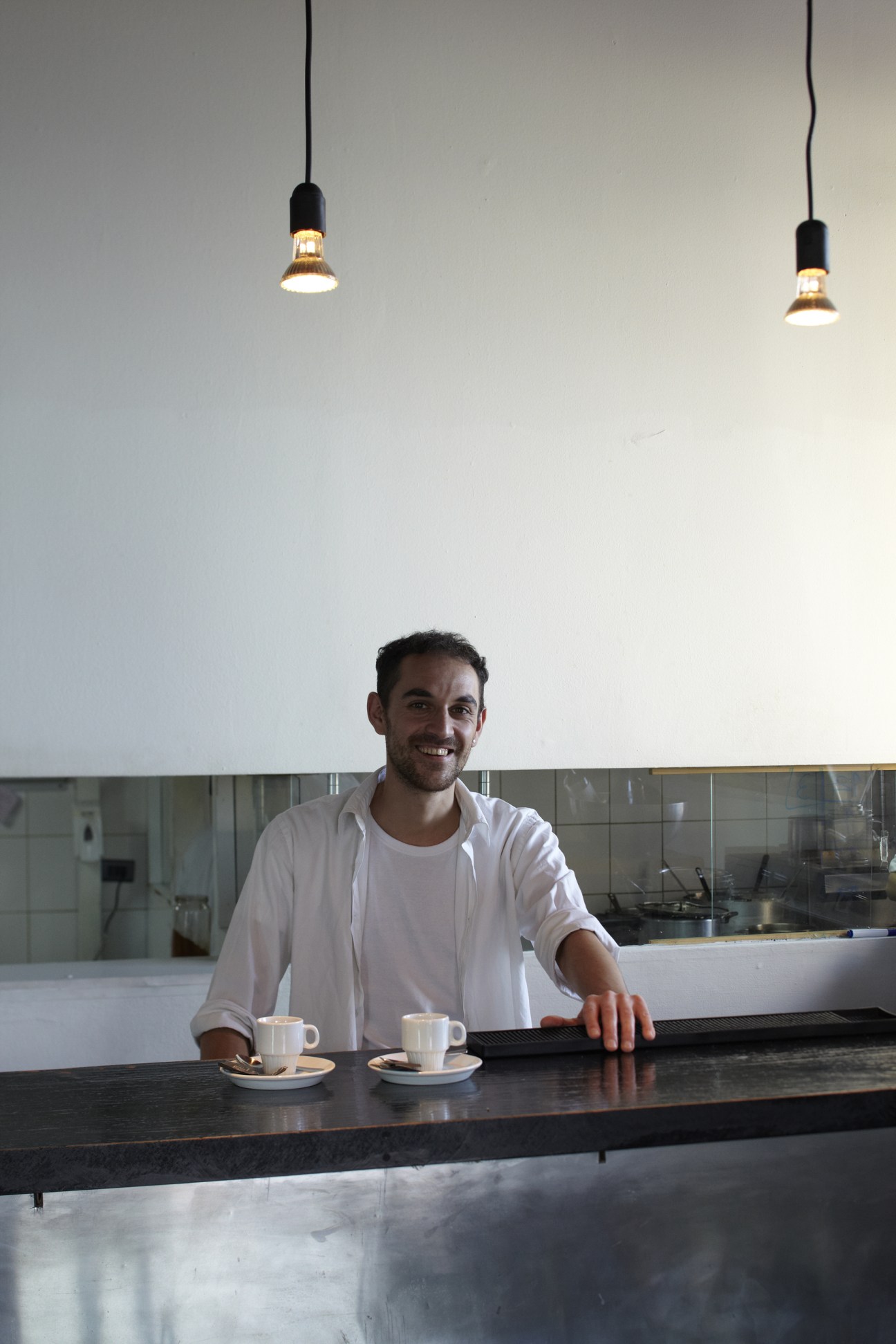 A smiling bartender stands behind a counter at Pasta e Vino restaurant in Valparaíso.