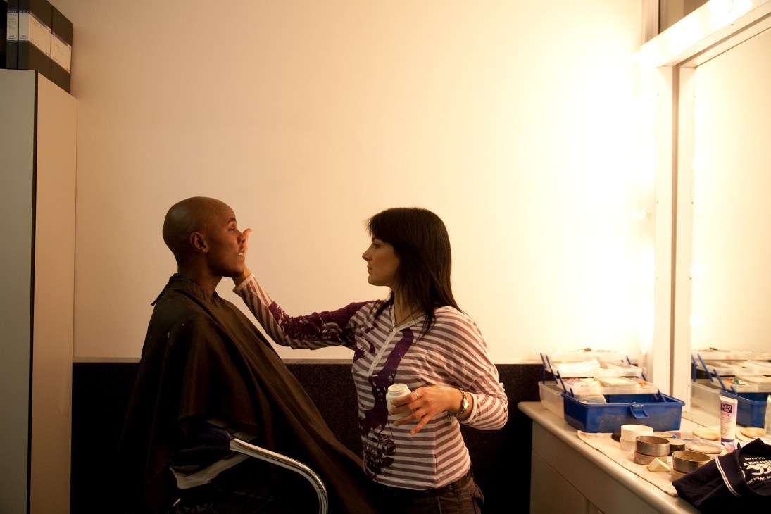 Thomas Mlambo, 'Soccer Africa' host, speaks with a woman in a striped shirt in a bright studio setting.