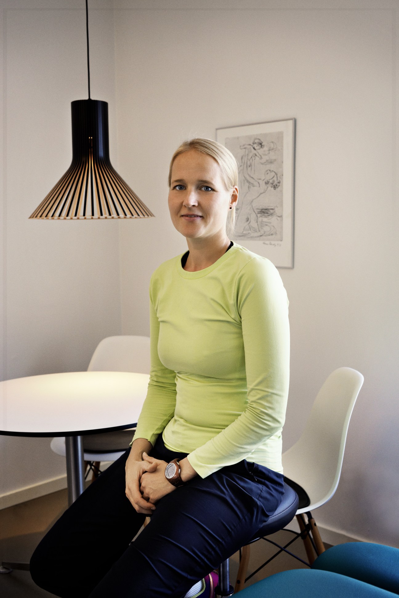 Physiotherapist Carina Ness sits at a white table beneath a black pendant light in the Center for Cancer and Health.
