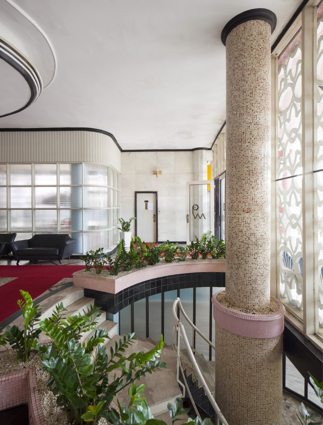 Main entrance lobby of Parque Verde Mar featuring a mosaic-tiled column, curved ceiling details, and decorative screen with plants.