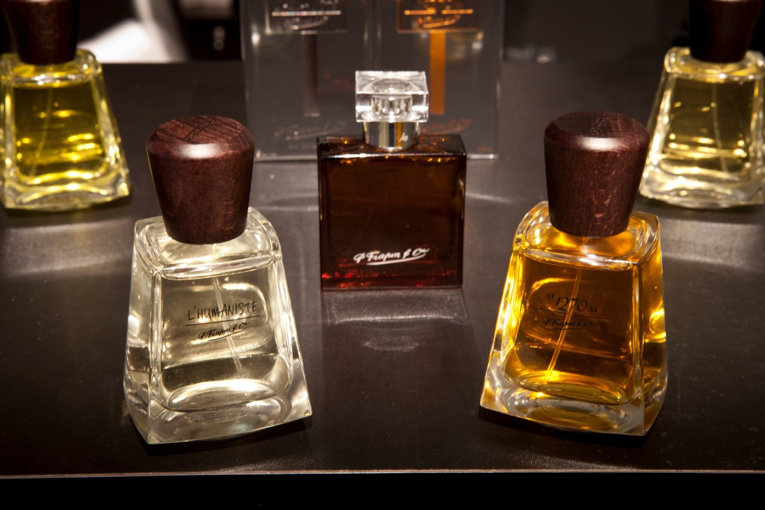 P Frapin & Cie perfume bottles with dark wooden stoppers displayed on black surface.