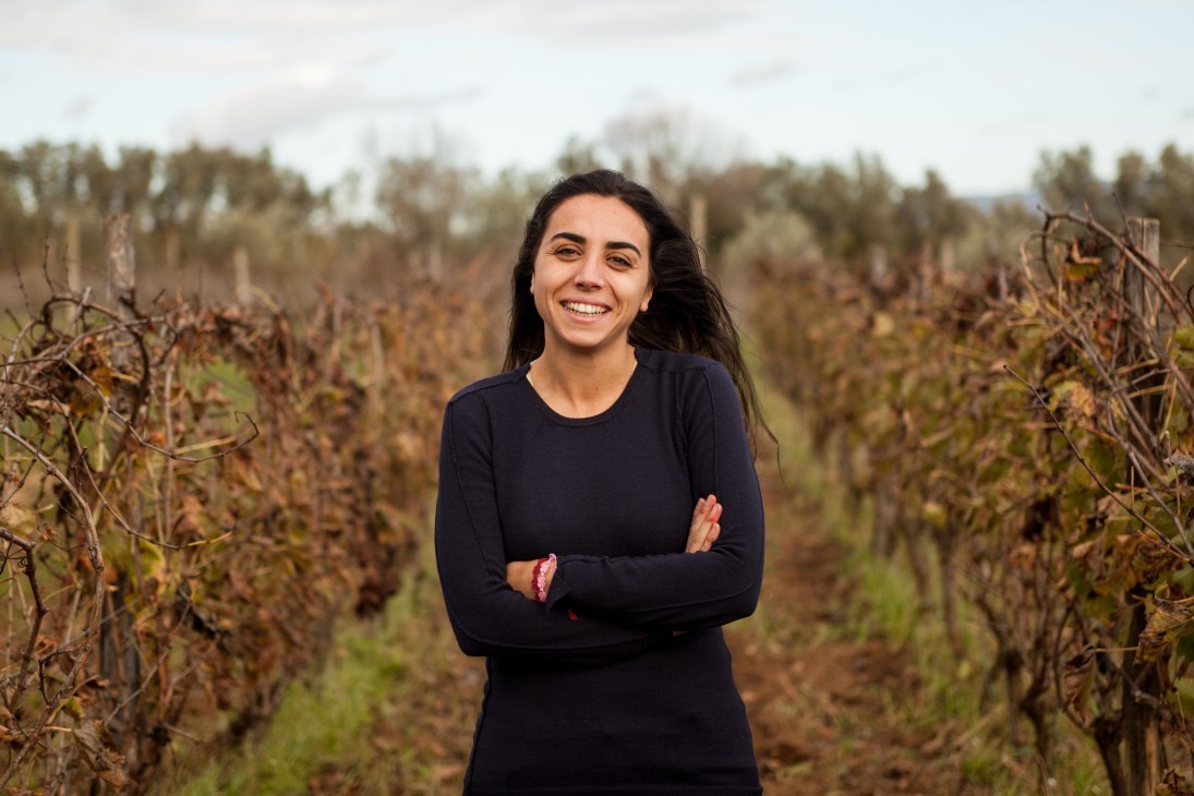 Woman standing in a vineyard of grapevines in Sicily.