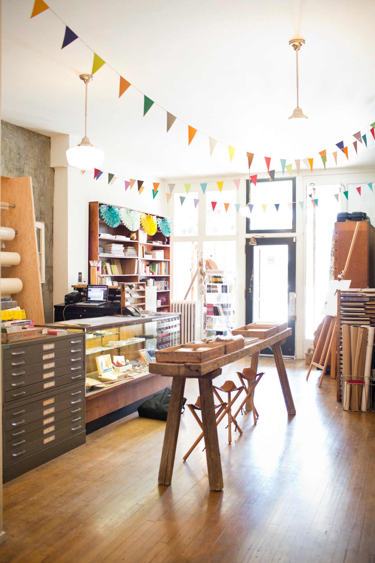 ARTiculations stationery shop interior with colorful bunting, wooden display tables, shelving, and art supplies.