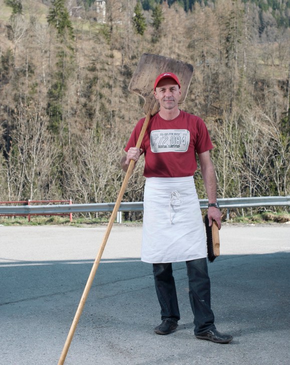 Pro Montagna baker Thomas Walker holding a large wooden shovel in front of a forested mountain backdrop.