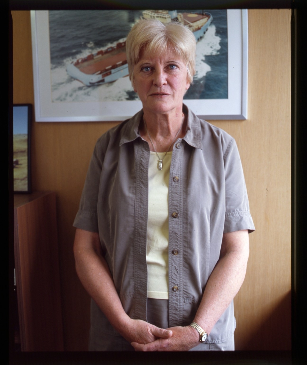 Phyl Rendell, Director of Minerals & Agriculture, stands in an office with a framed ship photograph behind her.