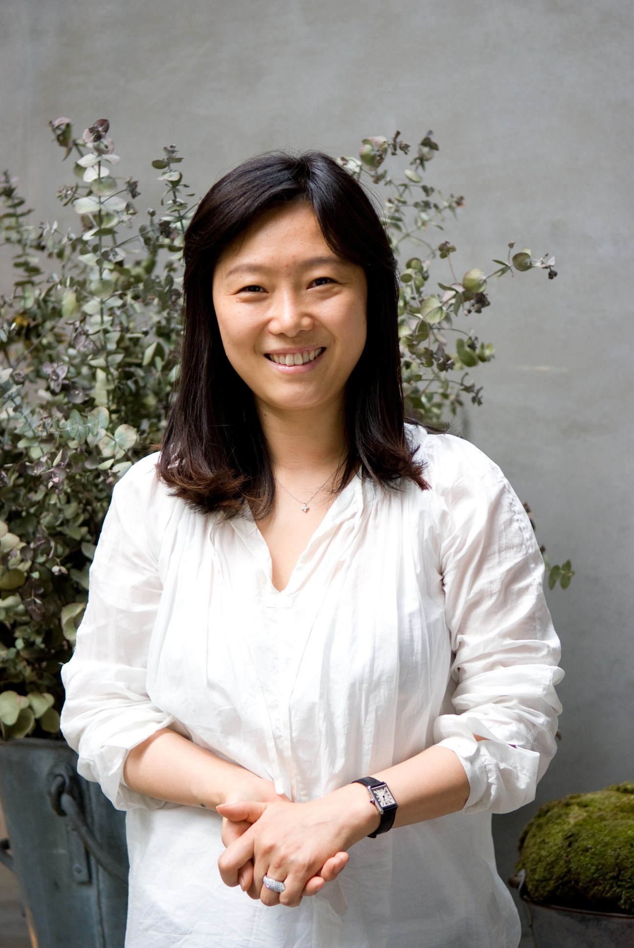 Joo Eun-ju, a fashion designer and boutique owner, smiles at the camera wearing a white shirt.