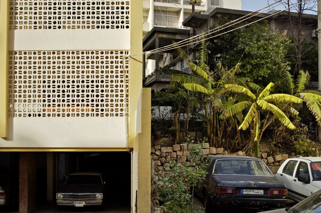 Modern yellow building with geometric facade pattern next to older concrete structures in Beirut's Sioufi neighborhood.