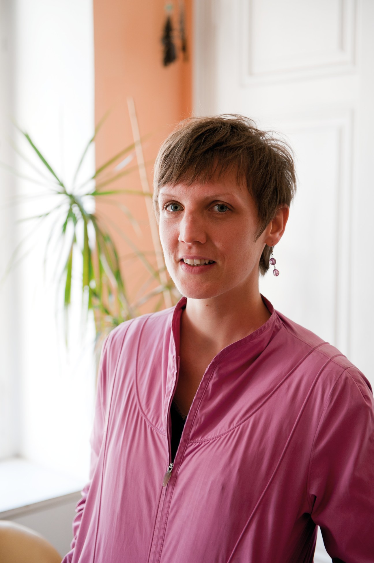 Portrait of Irene Moser, a Leopoldstadt resident, wearing a pink jacket in her apartment.