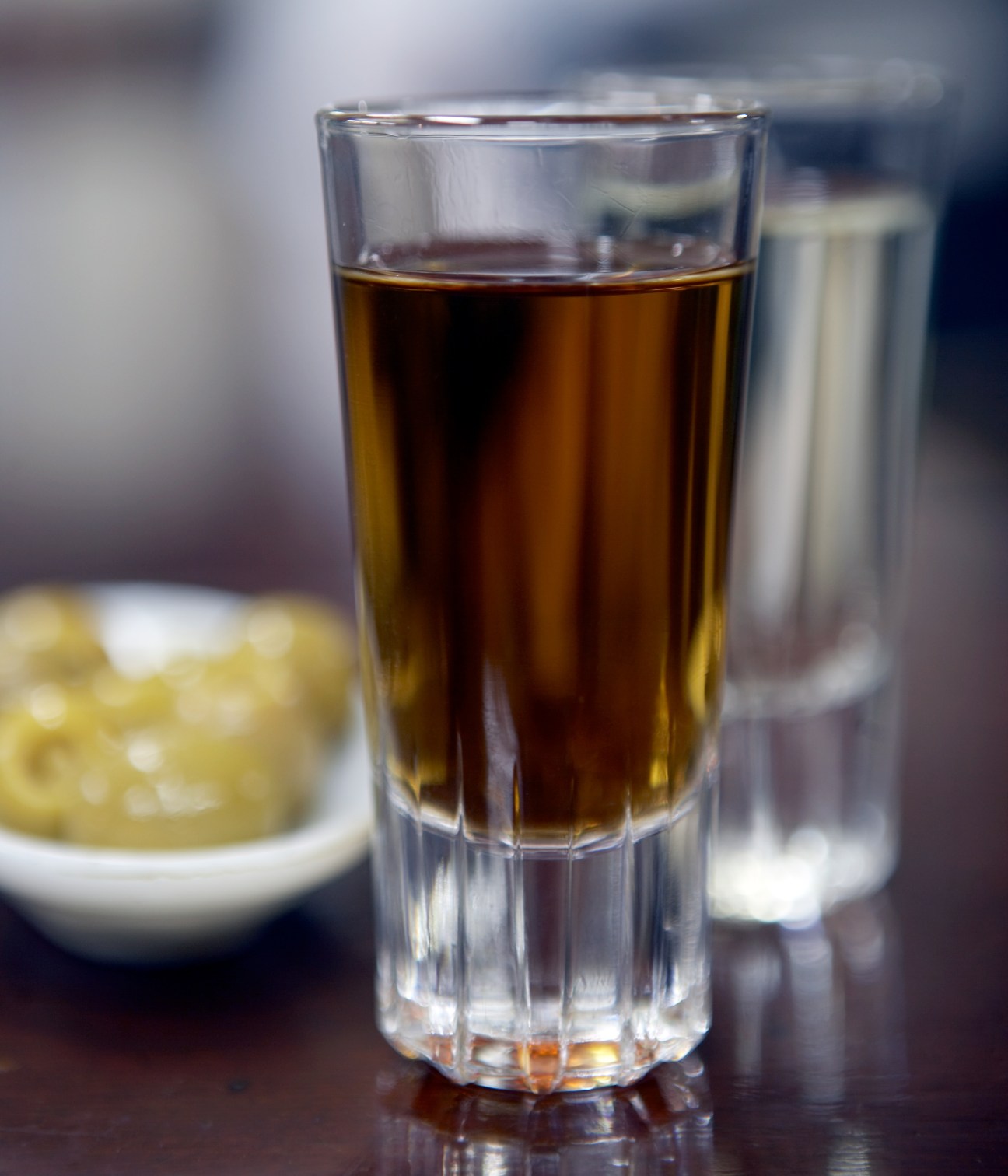 Glass of amber sherry with olives in background at Taberna La Manzanilla.