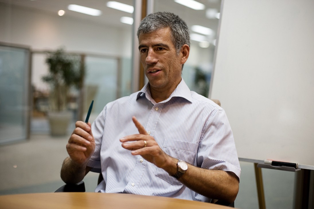 Paul Burkard, director of Bühler, speaks in a modern office setting while gesturing with his hands.