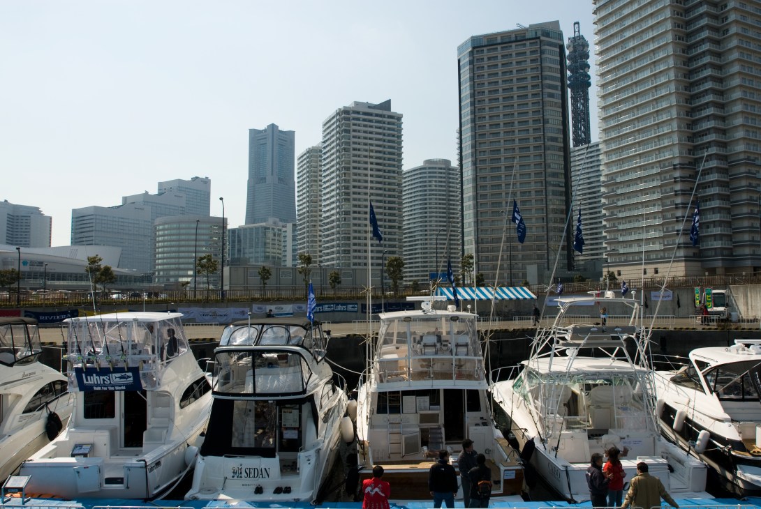 White boats moored in a marina with Yokohama's modern high-rise buildings in the background.