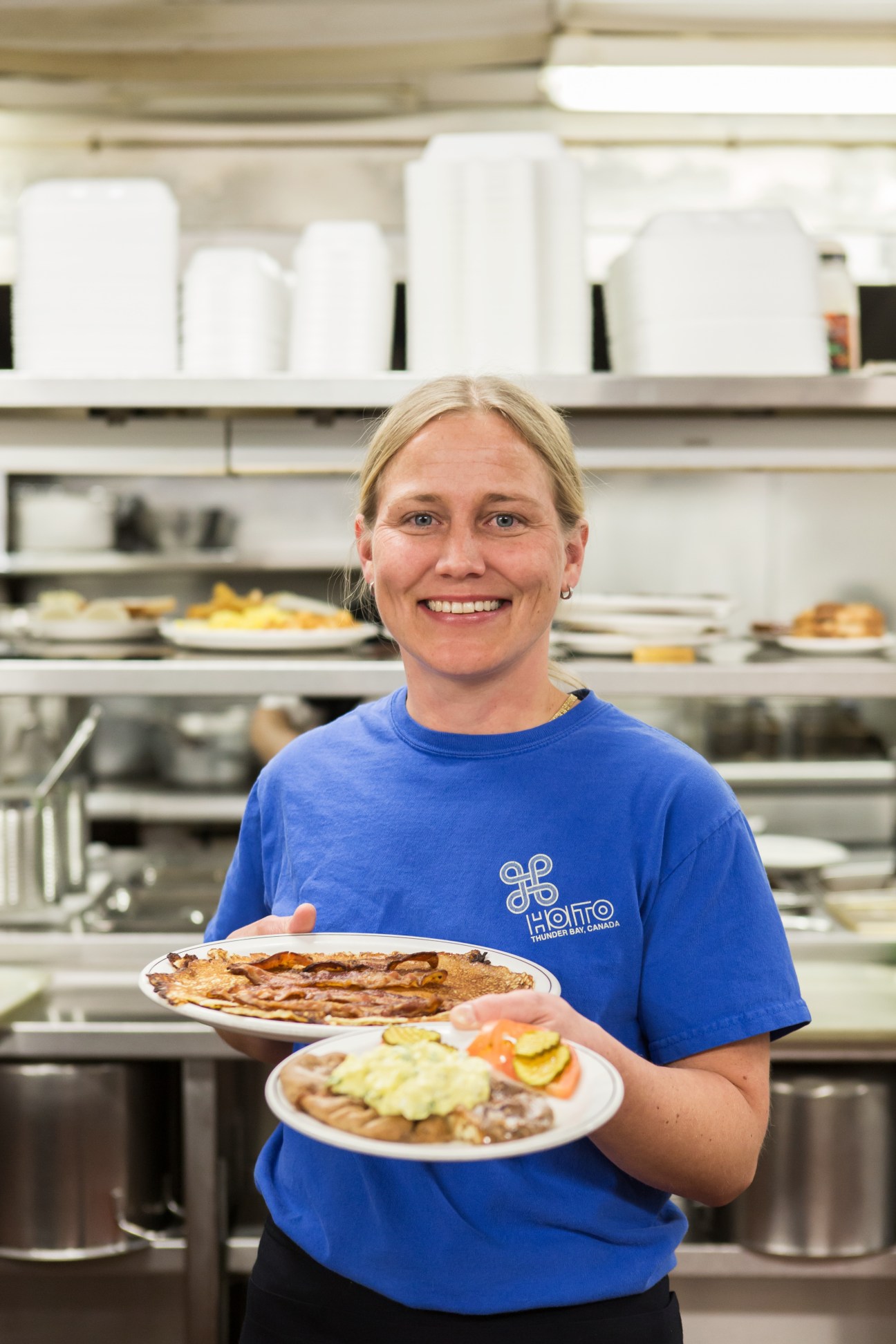 Suvi Sorri holds two plates of Finnish food in the Hoito restaurant kitchen.