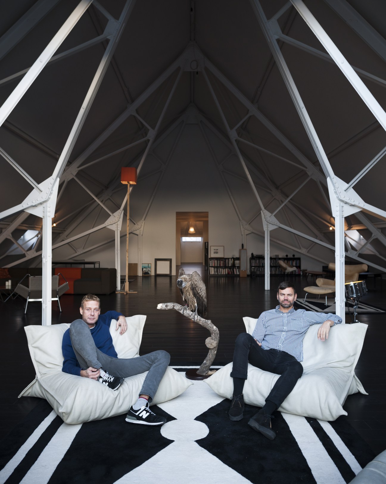 Michael Elmgreen and Ingar Dragset sit in white bean bag chairs inside their Berlin pumphouse studio with sculptural elements.