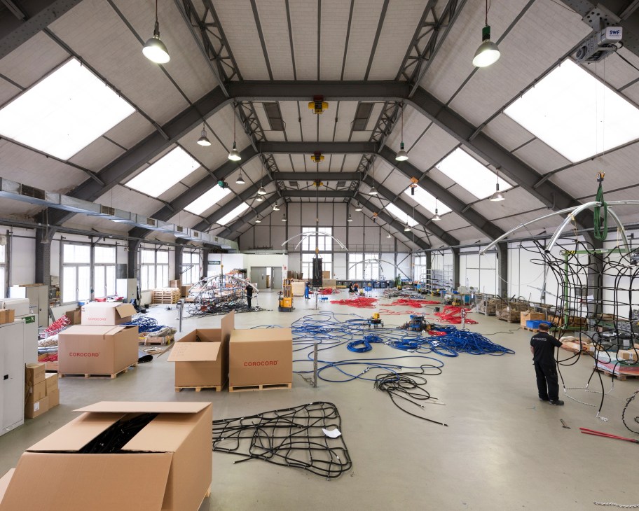 Corocord assembly hall in Berlin with colored ropes, cardboard boxes, and playground equipment components on the factory floor.