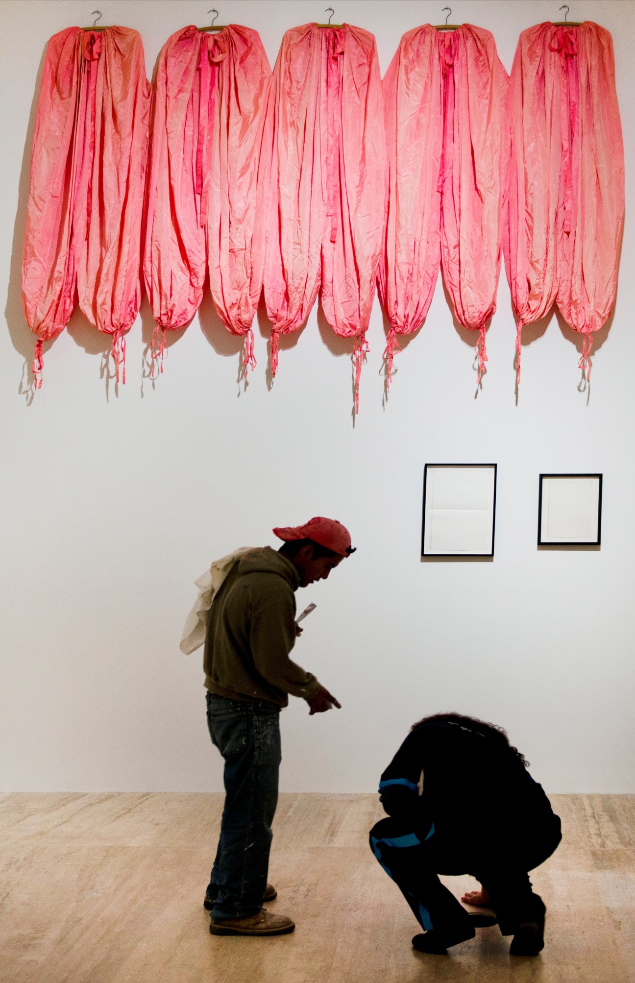 Two people preparing James Lee Byars' pink fabric installation artwork for display at Museo Jumex.