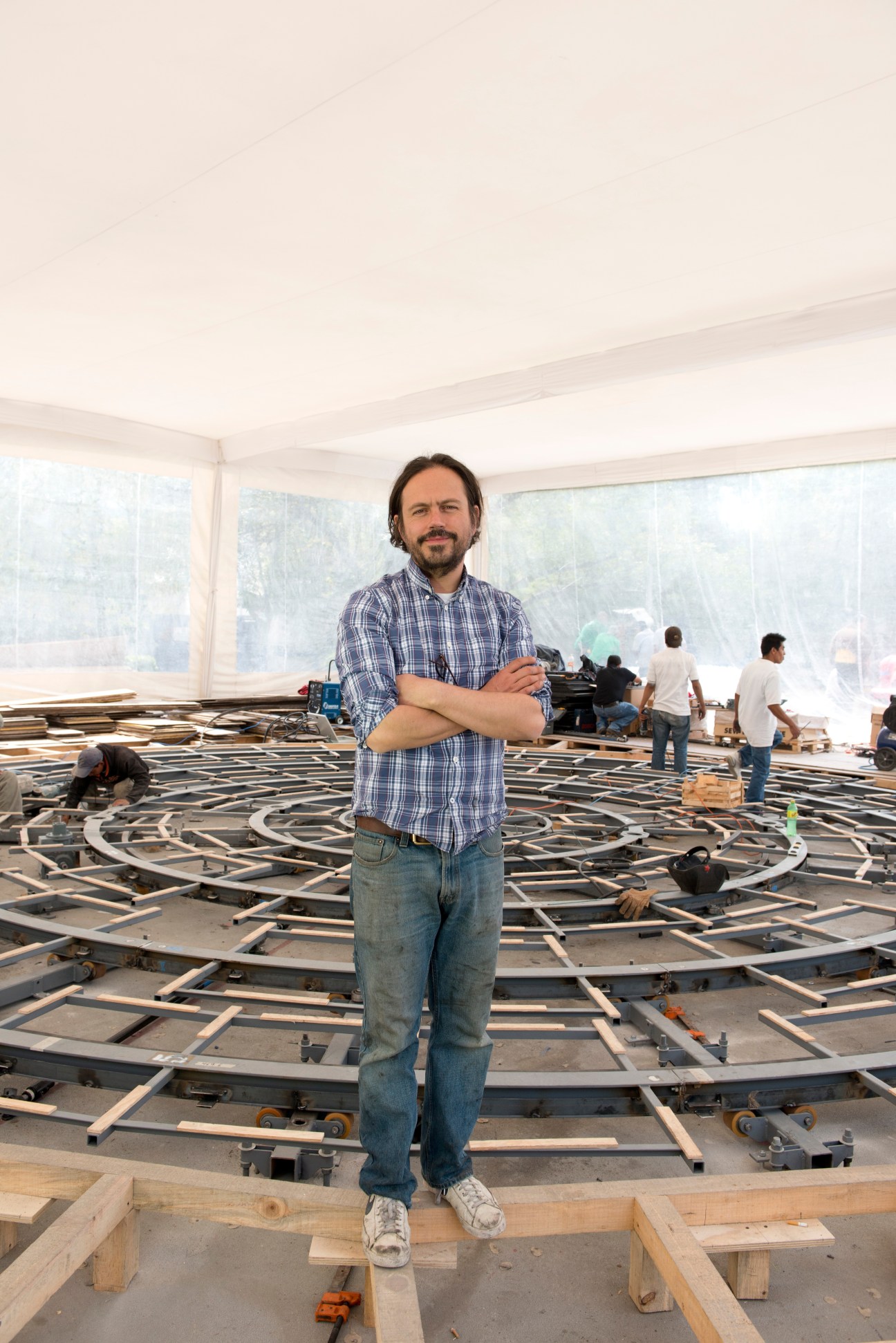 Mexican artist Damián Ortega stands in front of his mechanical sculpture installation 'Cosmogonía Doméstica' under construction.