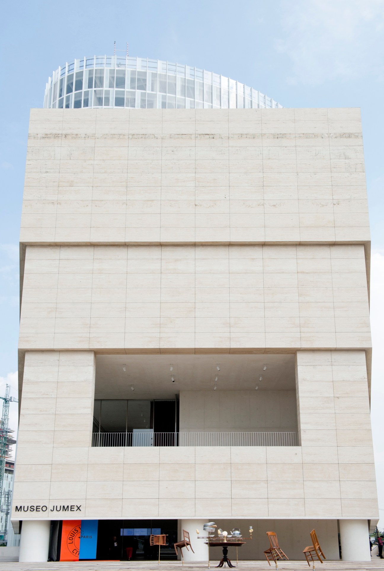 David Chipperfield-designed Museo Jumex building with cream travertine stone facade and curved glass upper level, showing entrance with signage.