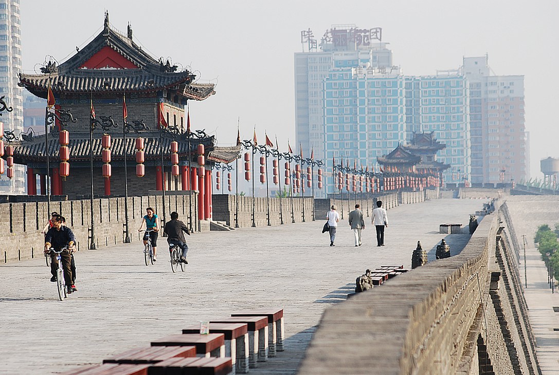 Ancient Chinese pavilion with red lanterns beside modern high-rise buildings in Beijing.