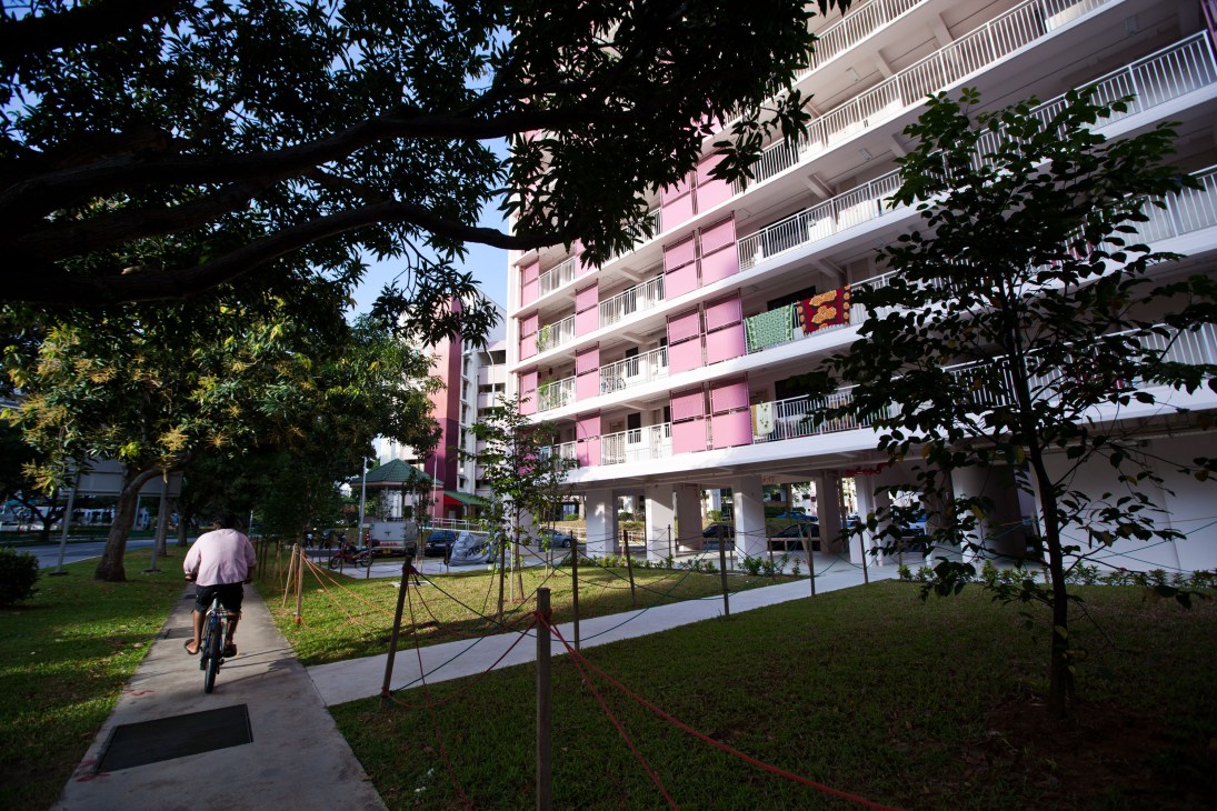 Modern pink and white apartment building with ground-level retail and landscaped grounds in Singapore.
