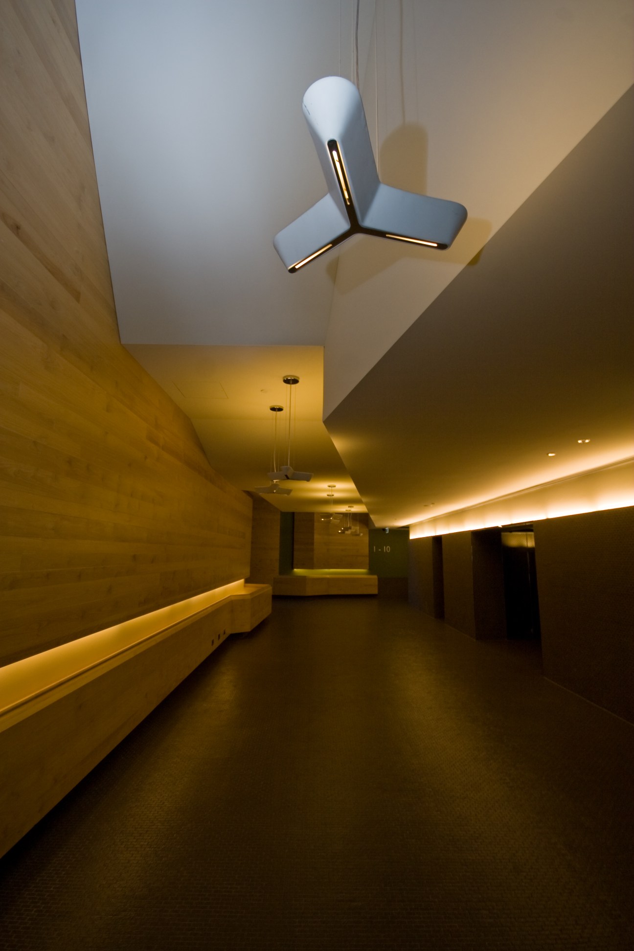 Modern foyer with warm golden lighting, white ceiling fan, and minimalist architectural design.