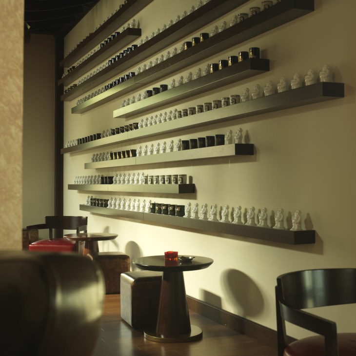 Modern restaurant interior with white bust sculptures arranged on illuminated shelves above dining tables.