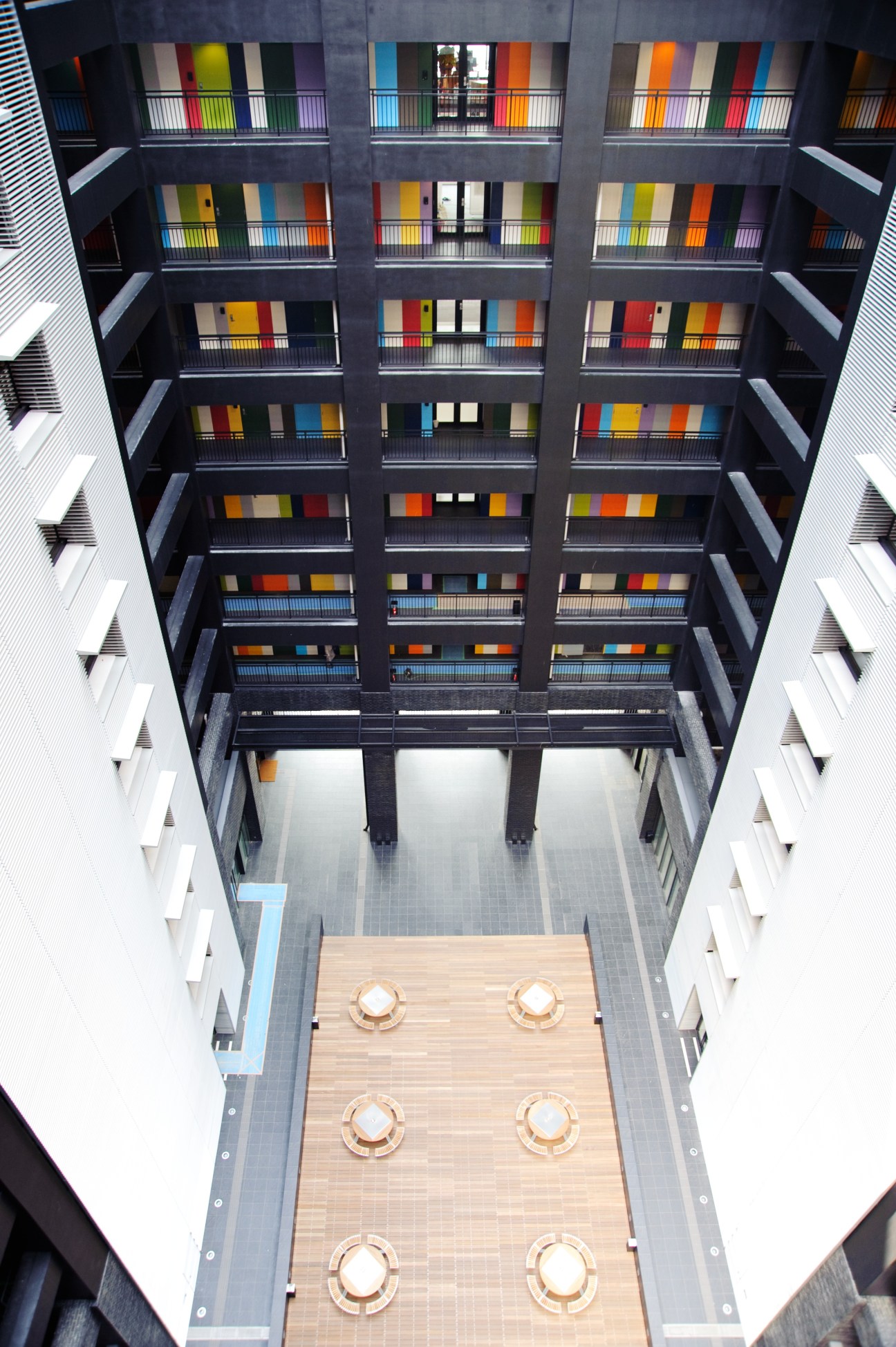 Overhead view of multi-coloured building interior courtyard with balconies and wooden central platform.