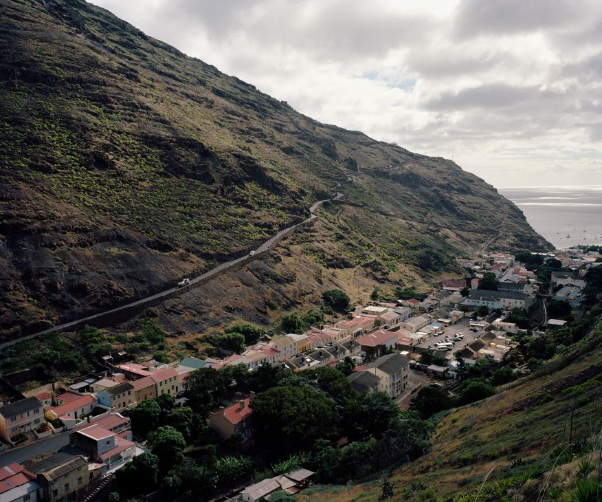 Steep volcanic hillside with winding road overlooking colorful buildings of Jamestown, St Helena.