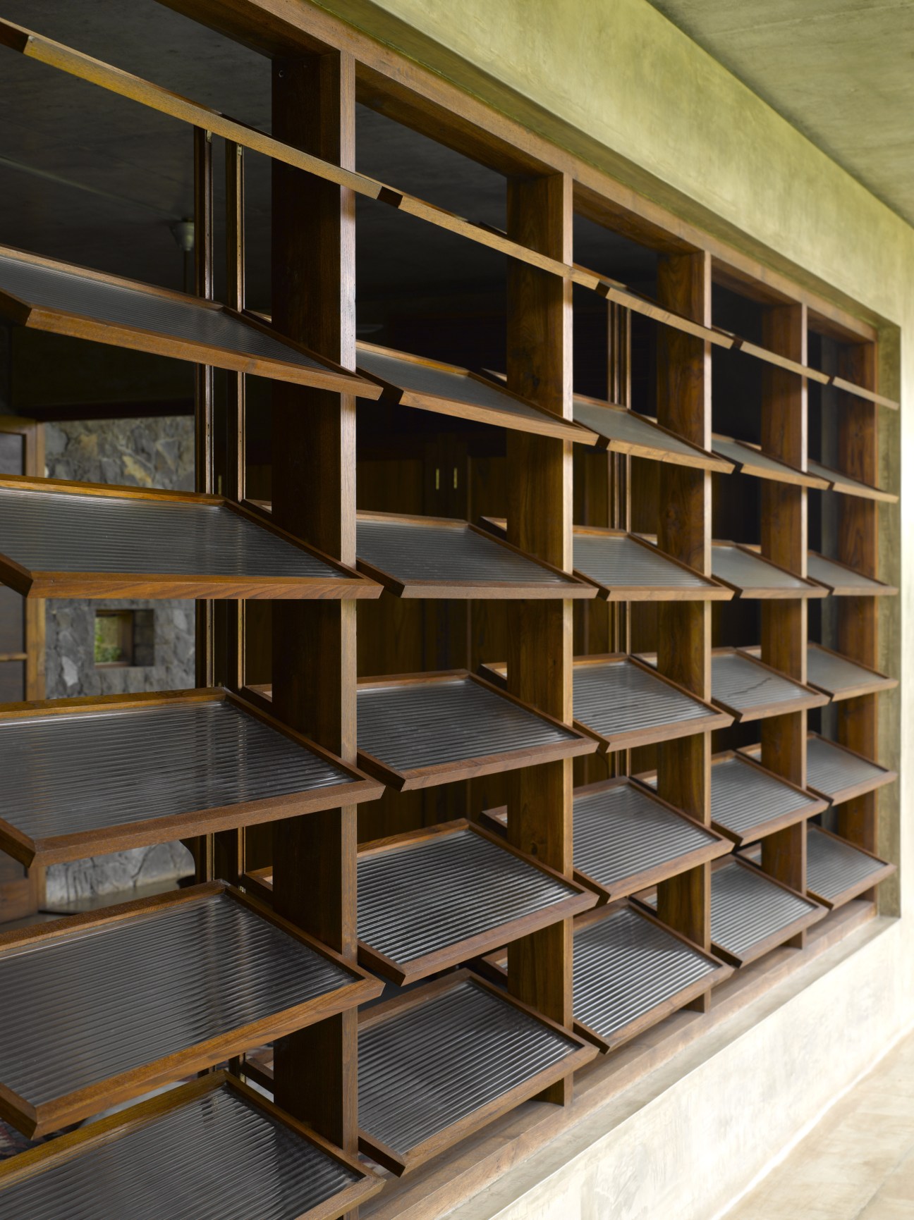 Wooden slatted wall screens with metal frames allowing light and air circulation through the architecture.