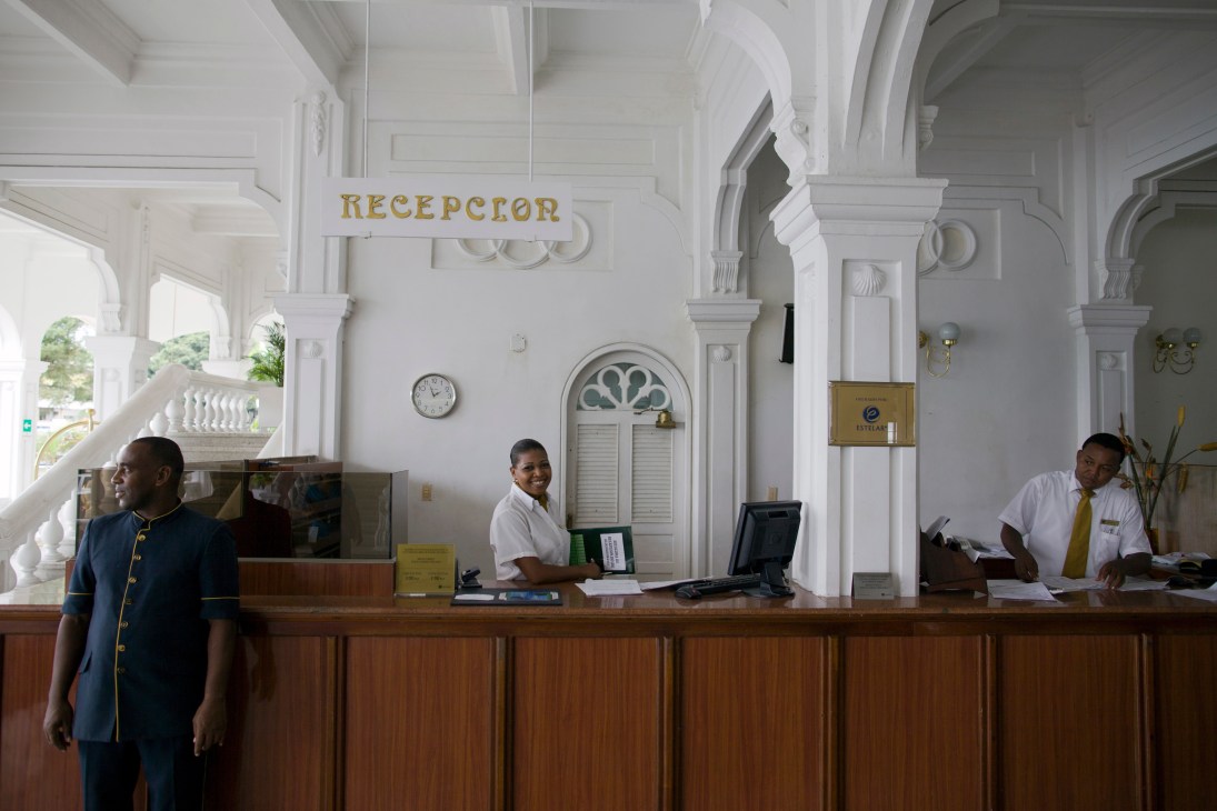 Hotel Estación reception desk with white neoclassical columns and staff in uniforms.
