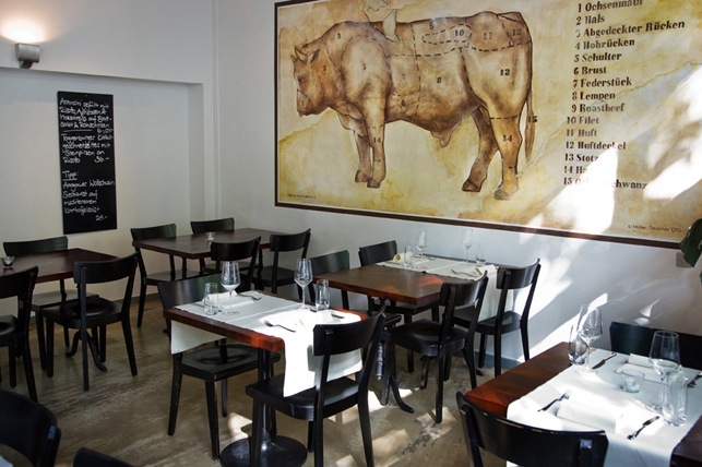 Interior of Cafe Boy restaurant with tables, chairs, and butcher diagram on wall.