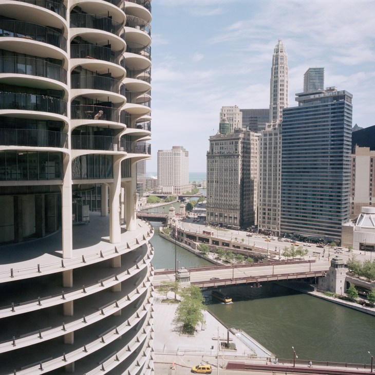 Curved scalloped balconies of Marina City tower with Chicago River and skyline view in background.