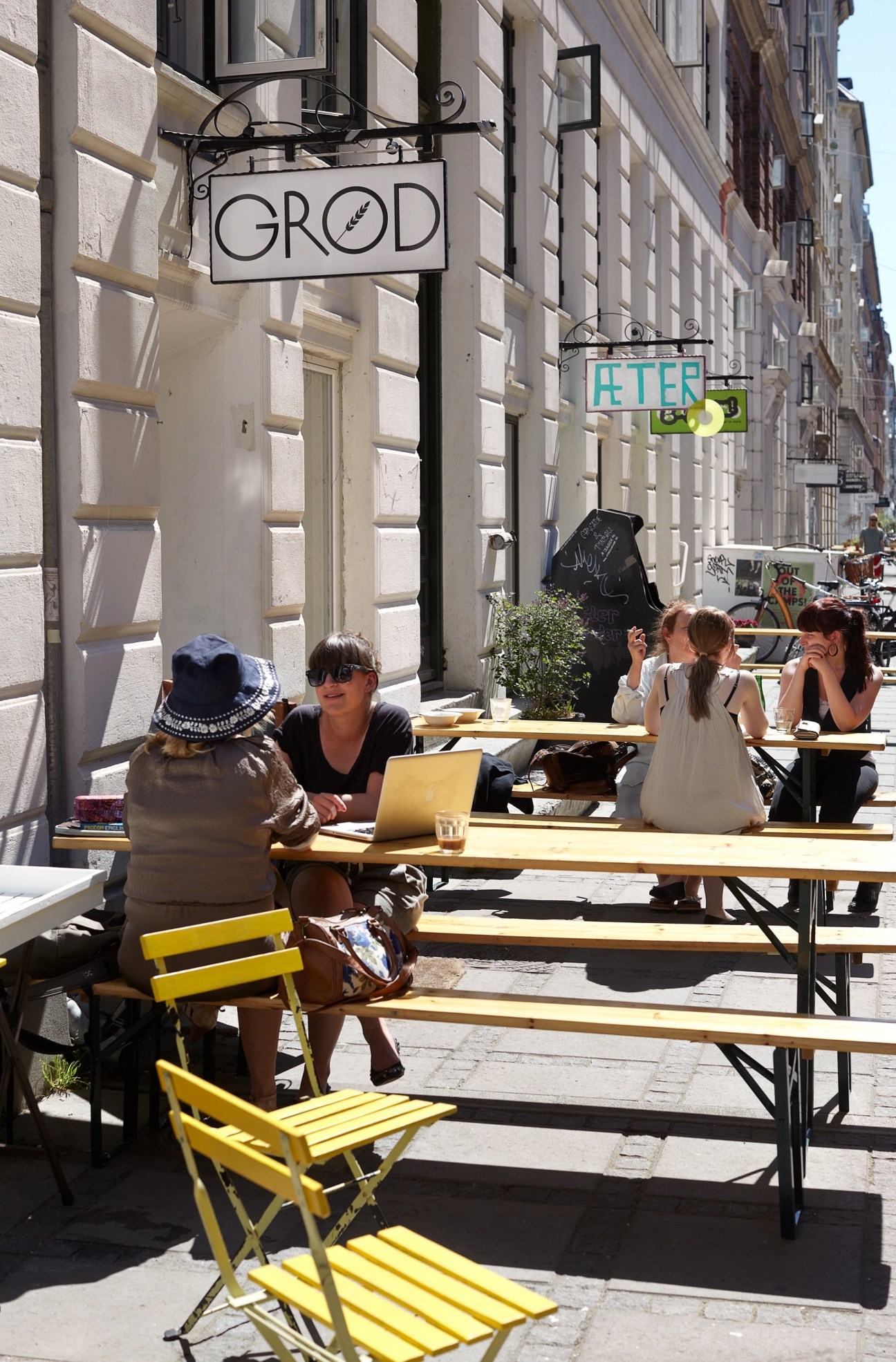 Outdoor café with yellow chairs and tables under a sign reading "GROD" on a Copenhagen street.