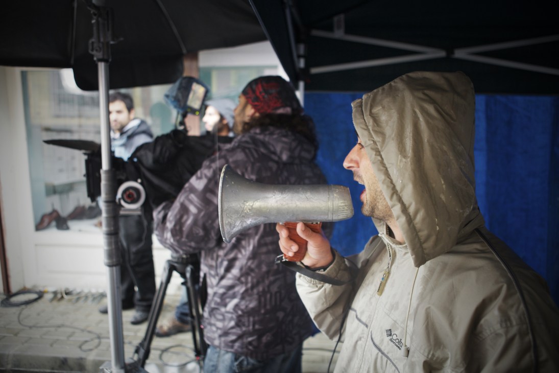 Director holding megaphone giving directions to crew on Istanbul film set at night.